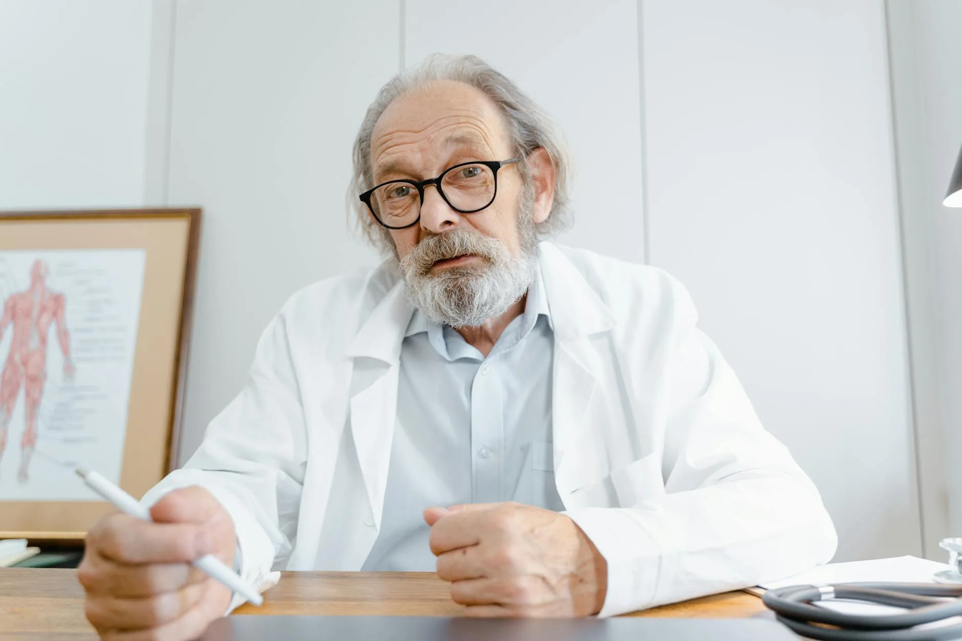 Krwawienie po menopauzie: jakie badania wykryją raka endometrium na wczesnym etapie Starszy lekarz w gabinecie, z długopisem w dłoni, podczas teleporady