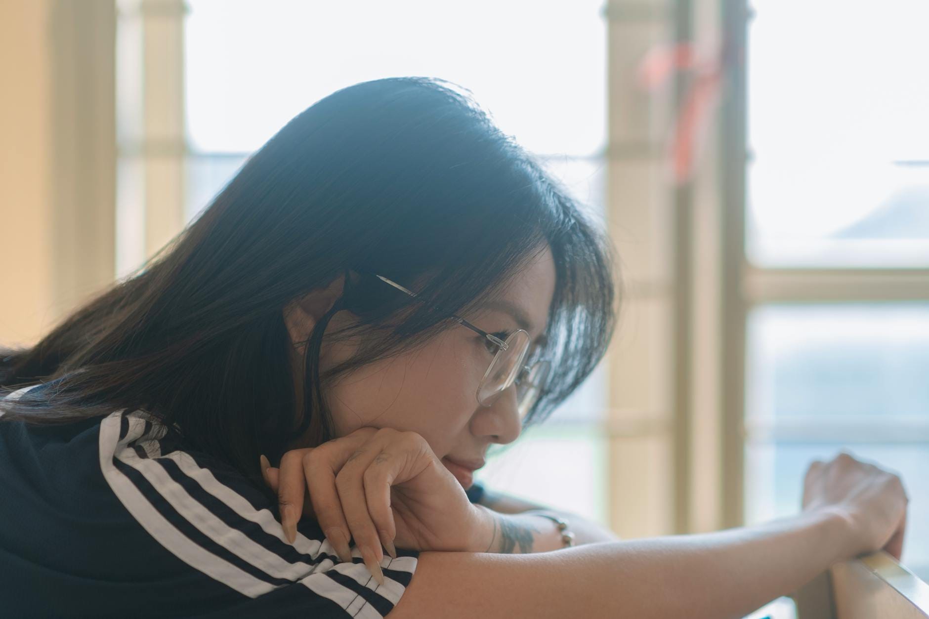 Zamyślona kobieta przy oknie, rozważająca zmiany w swoim cyklu